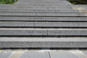 入口を経てミュージアム施設に向かう階段には聖火リレー最終ランナーの名前が刻まれている、1964年の東京オリンピックは坂井義則氏