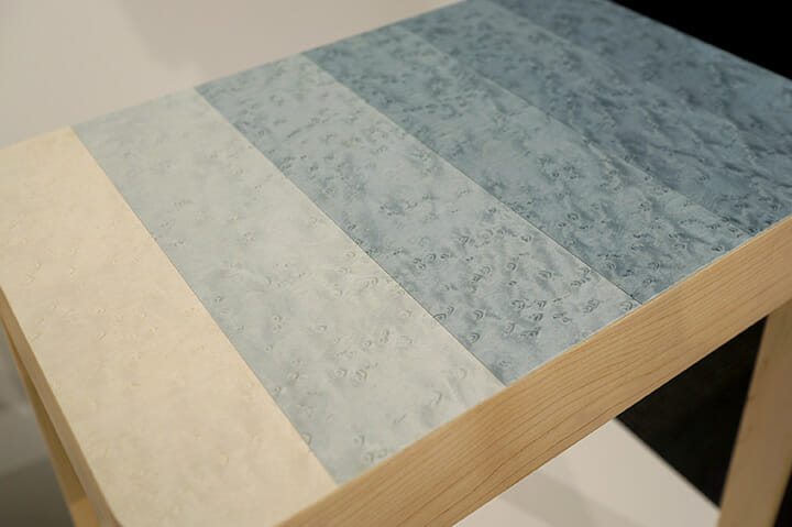 「MATERIAL DESIGN EXHIBITION」にて、小池和也さんによる「decresc series」、岐センの染色ツキ板を使った提案、木目は連続しているが色が段階的に変わり、フラットな家具が立体感や奥行きを伴って見えます