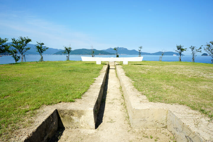 「境界線の庭」土井満治。災害で出た土砂で埋めたてられた土地に鳥居に見立てた石彫が展示