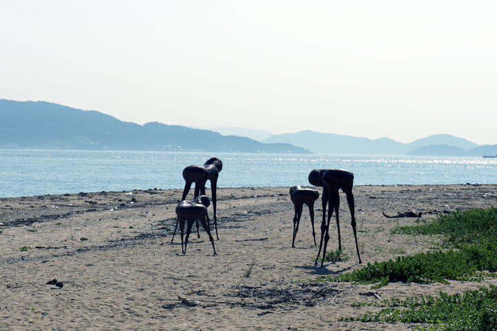 「怪物と少年Ⅱ/この彫刻は一万年の生命を持ちヒトの一生の間には10mほど歩くⅢ」伊東敏光。浜辺に佇む4頭の怪物がはじめは不気味でしたが、だんだん神聖な生き物に見えてきます