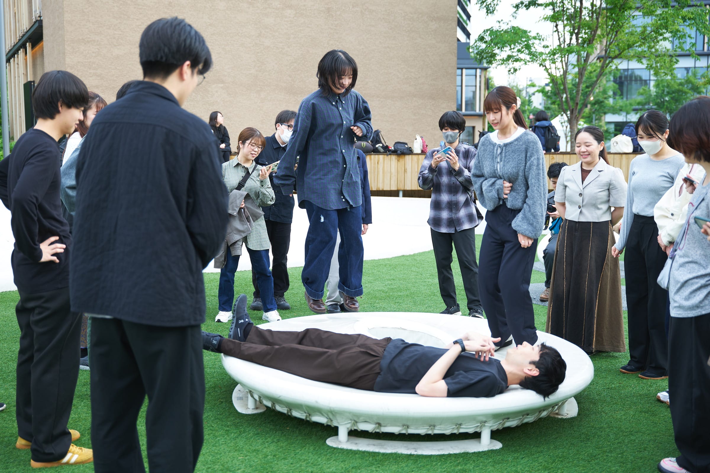 ドーナツ型の遊具に寝転がる田嶋さんと、その周りで飛び跳ねる参加者